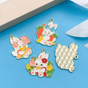 Macro detail of enamel Easter bunny charms with floral carrot motifs and gold textured back
