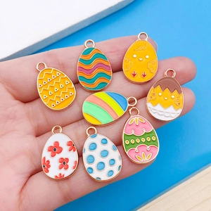 Acht farbenfrohe Emaillie-Ostereier-Anhänger mit Goldlegierung auf der Hand präsentiert