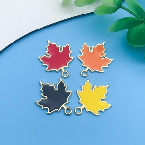Macro shot of maple leaf charms in four colors with gold edges and enamel finish