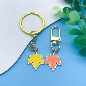 Detail of maple leaf pendants with enamel finish in yellow and orange on gold keychains