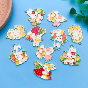 Bunte Emaille-Anhänger mit Ostermotiven wie Hasen, Erdbeeren und Blumen auf Blau