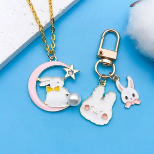 Detail of bunny and moon pendants with pearls and enamel on gold chain necklaces