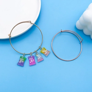 Detail von verstellbaren Metallarmbändern mit bunten Harz-Bonbon-Anhängern und Glitzerschrift
