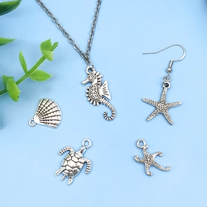 Detailed close-up of antique silver sea turtle, starfish, and seahorse charms for DIY jewelry