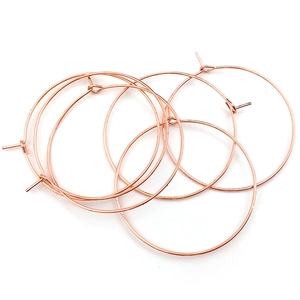 Detalle de cinco aros para pendientes DIY en oro rosa sobre un fondo blanco impecable