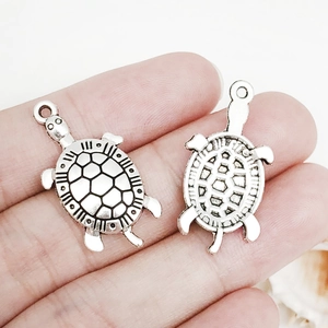 Macro shot of two vintage silver turtle charms showing front and back detail for DIY jewelry