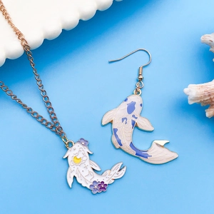 Detail of koi fish jewelry set with purple scales and golden accents on blue background