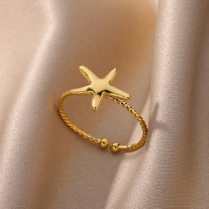 Anello stella marina in oro 18K con fascia intrecciata su sfondo di seta beige