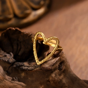 Anillo de corazón abierto en oro martillado a mano con superficie texturizada sobre madera