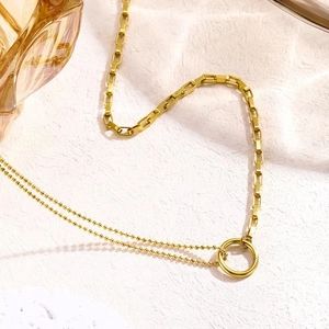 Macro detail of gold layered necklace featuring a minimalist geometric circle pendant