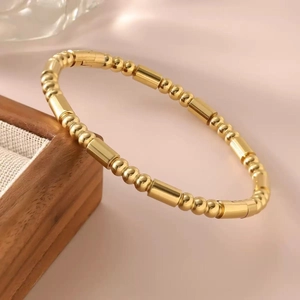 Bracelet jonc élégant plaqué or 18k avec texture perlée sur fond en soie rose