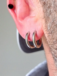 Vue détaillée de créoles argentées et d'un clou noir sur cartilage d'oreille au style épuré