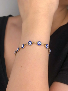Vue détaillée du bracelet œil protecteur avec chaîne dorée au poignet d'une femme