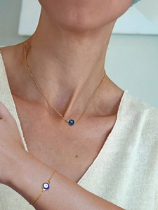 Vue détaillée du collier et bracelet œil porte-bonheur dorés portés par un mannequin