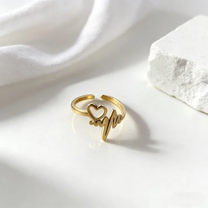 Primer plano detallado del anillo dorado con latido de corazón en seda blanca elegante