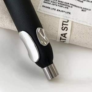 Détail d'une bague minimaliste noir mat avec accents argentés fluides sur fond doux