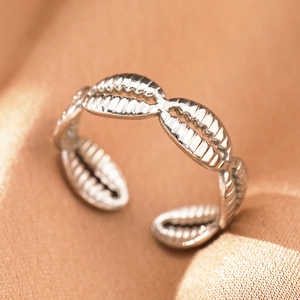 Detailed macro view of silver adjustable ring with shell texture on beige fabric