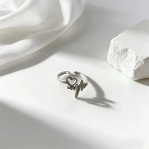Detalle de anillo de acero inoxidable plateado con patrón de corazón y latido
