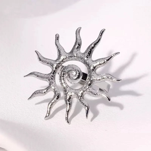 Detalle del broche de sol plateado con textura de espiral y acabado de metal martillado
