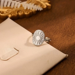 Dettaglio anello in acciaio inossidabile argento con goffratura radiale su sfondo vintage
