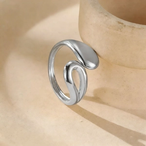 Detail of a silver liquid-metal style ring on a textured beige ceramic bowl edge