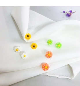 Detailed view of colorful daisy stud earrings in white yellow green and orange resin