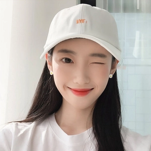 White cotton baseball cap with orange MT embroidery and small daisy earrings for women