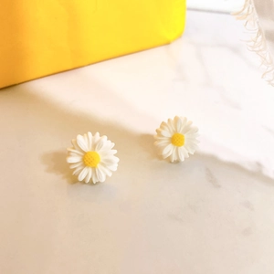 Macro detail of S925 daisy stud earrings with white petals and yellow centers
