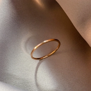 Gros plan d'une bague fine minimaliste en or rose sur fond de soie élégant