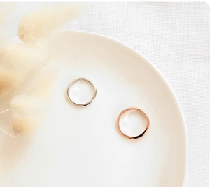 Primer plano de anillos minimalistas de acero de titanio plateado y oro rosa en bandeja