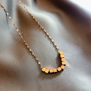 Collier en or rose avec fine chaîne torsadée et huit pendentifs carrés sur soie
