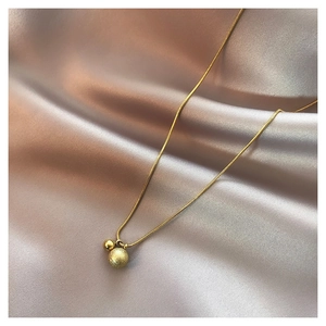 Macro-opname van gouden slangenketting met gepolijste en matte kralen op zijden stof
