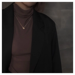 Detail van een gouden ketting met matte kraal hanger gedragen door een model