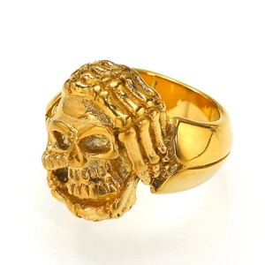 Macro shot of gold skull ring with skeletal hand detailing in polished stainless steel