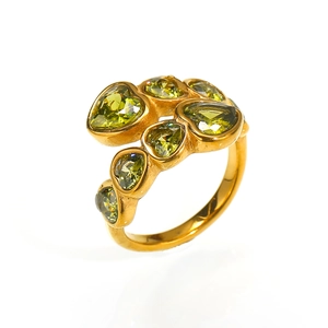 Detail of interlocking hearts ring featuring olive green zircons on gold-plated metal