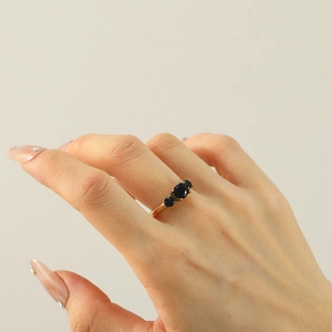 Detail van een elegante 18k vergulde ring met drie fonkelende blauwe zirkonia steentjes