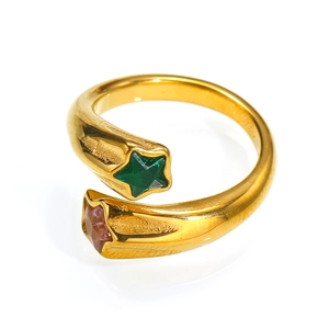 Detail of 18K gold star ring featuring green and pink zircon stones on a white surface