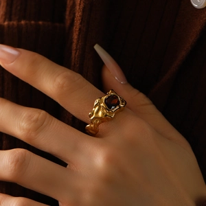 Lavatexturierter Titanstahlring mit tiefrotem Edelstein an der Hand des Models