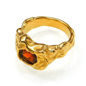 Makroaufnahme eines goldenen Rings mit Lavatextur und orangefarbenem Edelstein
