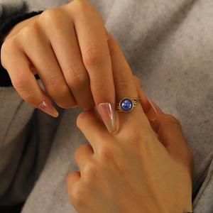 Detail of vintage gold ring featuring a blue round gemstone and ornate floral engravings