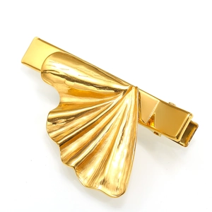 Detailed view of the wavy metallic texture and duckbill clip on this golden hair clip