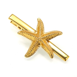 Macro detail of golden starfish hair clip with textured relief and duckbill clamp