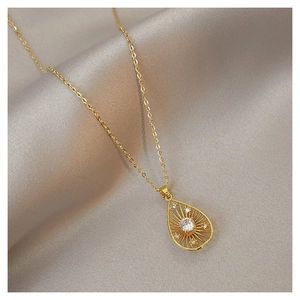 Detailed view of a gold teardrop pendant with sunburst texture and central gemstone