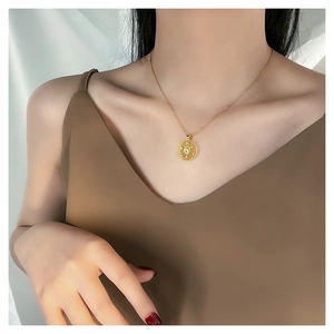 Close-up of a gold starburst pendant necklace with a central zircon on a female model