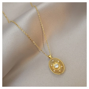 Macro view of gold oval pendant featuring a sunburst motif and sparkling zircon stone