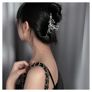 Close-up of liquid silver hair claw clip with irregular aesthetic design on wavy hair