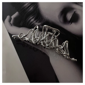 Macro detail of large liquid metal hair claw clip with irregular silver wave design