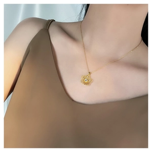 Close-up of a gold floral pendant necklace with a zircon stone on a female collarbone
