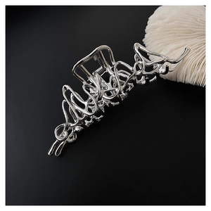 Macro shot of silver liquid metal hair claw clip with polished finish on black background