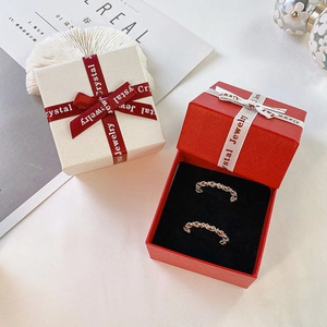 Close-up of golden woven texture rings in a red gift box with white silk ribbon